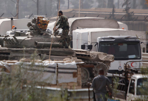 Red Crescent trucks are seen parked near Syrian solders at a checkpoint near Wafideen camp in Damascus 