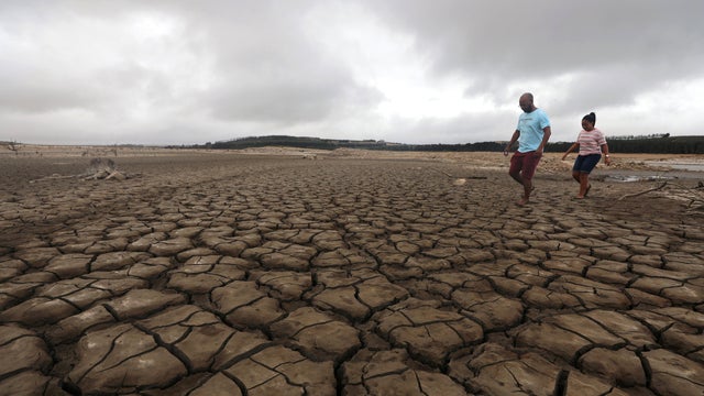 A family negotiates their way through caked mud around a dried up section of the Theewaterskloof dam near Cape Town, South Africa, Jan. 20, 2018. 