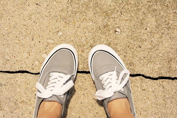 Feet stepping on a sidewalk crack 