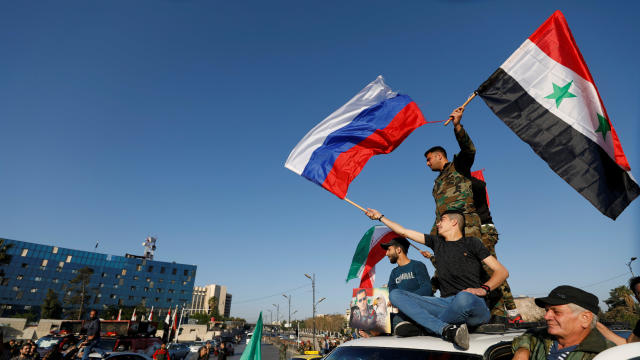 Syrians wave Russian and Syrian flags during a protest against U.S.-led air strikes in Damascus 