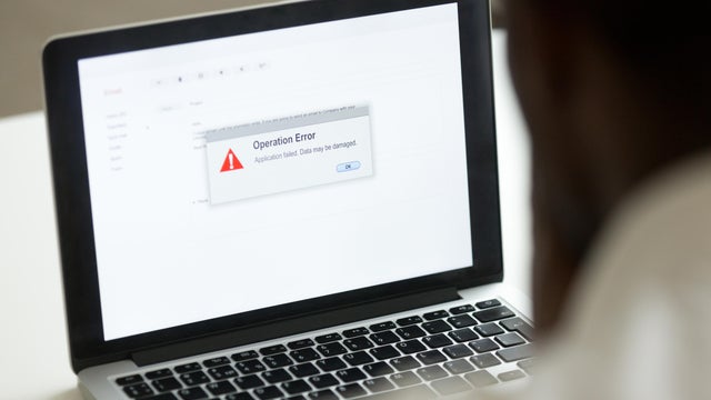 African man using laptop with application failure message on screen 