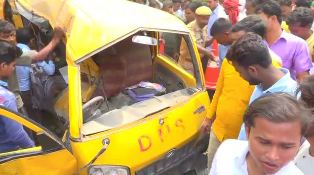 People gather around a school bus after it collided with a train in Uttar Pradesh 