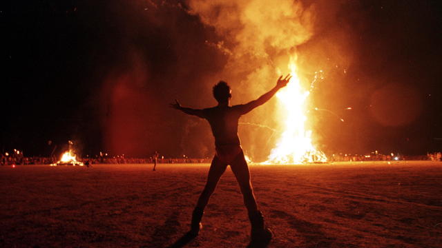 A "Burning Man" participant holds up his arms as t 