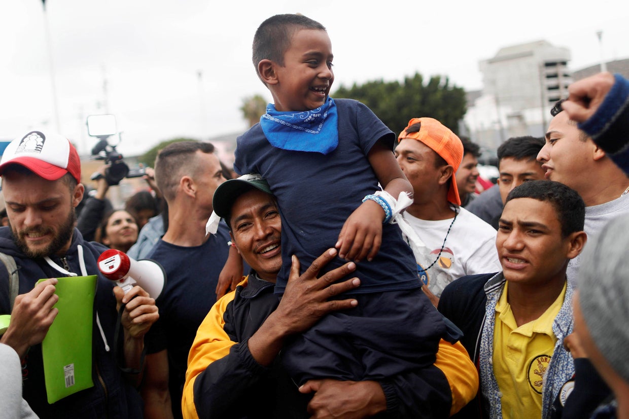 A man and his son, members of a caravan of migrants from Central America, react near the San Ysidro checkpoint as the first fellow migrants entered U.S. territory to seek asylum on Monday, in Tijuana 