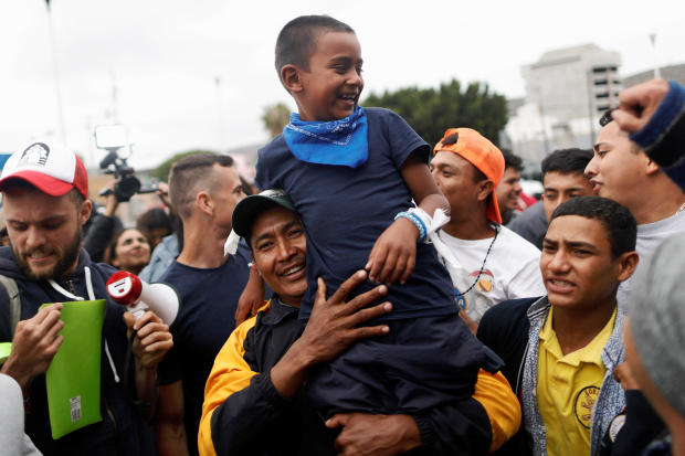 A man and his son, members of a caravan of migrants from Central America, react near the San Ysidro checkpoint as the first fellow migrants entered U.S. territory to seek asylum on Monday, in Tijuana 