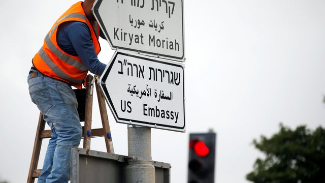 A worker hangs a road sign directing to the U.S. embassy, in the area of the U.S. consulate in Jerusalem 