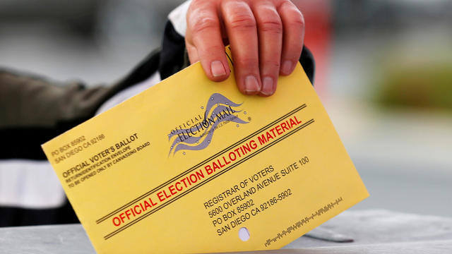FILE PHOTO: A poll worker places a mail in ballot into a voting box as voters drop off their ballot in the U.S. presidential primary election in San Diego, California 