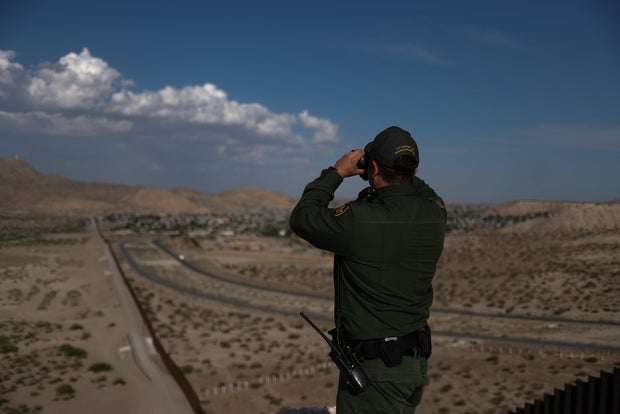 Border patrol agent uses binoculars to search for illegal immigrants along U.S. border with Mexico in Sunland Park, New Mexico,