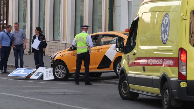 A police officer stands next to a damaged taxi, which ran into a crowd of people, in central Moscow 