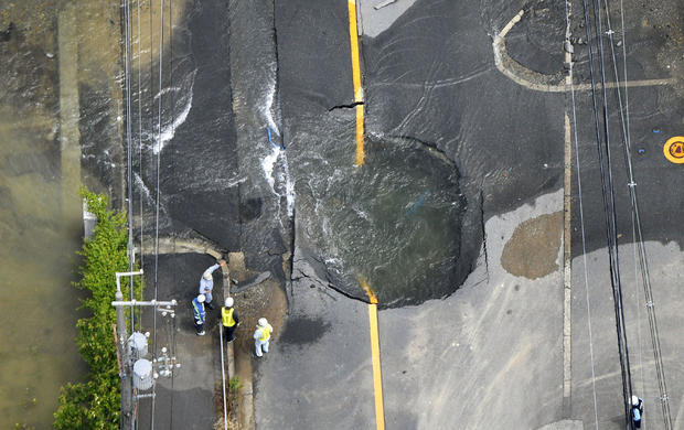 Water flows out from cracks in a road damaged by an earthquake in Takatsuki 
