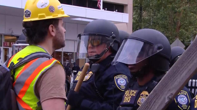 A protester faces a Department of Homeland Security agent outside an Immigration and Customs Enforcement facility in Portland, Oregon, early on June 28, 2018. 