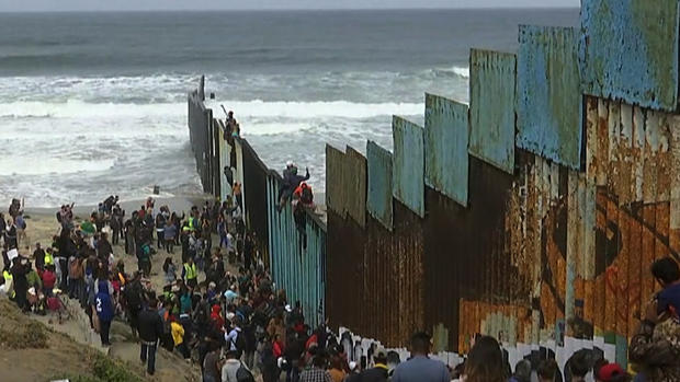 Immigrants Climbing Over Border Wall 