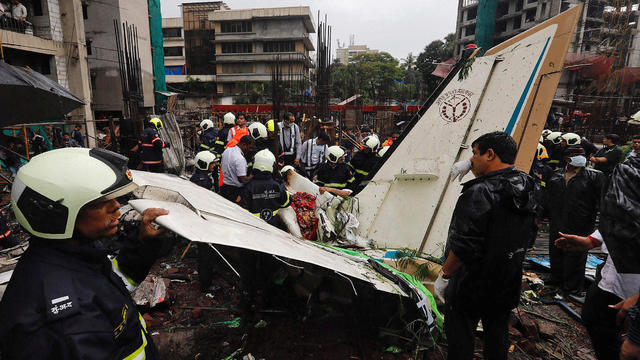 Firefighters inspect the site of a plane crash in Mumbai 