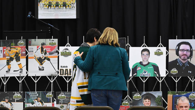 Mourners comfort each other as they look at photographs before a vigil at the Elgar Petersen Arena, home of the Humboldt Broncos, to honour the victims of a fatal bus accident in Humboldt 