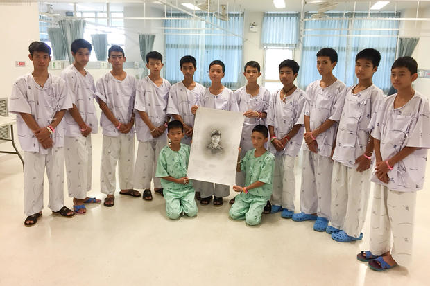 The 12-member "Wild Boars" soccer team and their coach rescued from a flooded cave pose with a drawing picture of Samarn Kunan, a former Thai navy diver who died working to rescue them at the Chiang Rai Prachanukroh Hospital, in Chiang Rai 