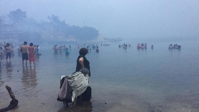 People are seen as a wildfire burns in Mati 