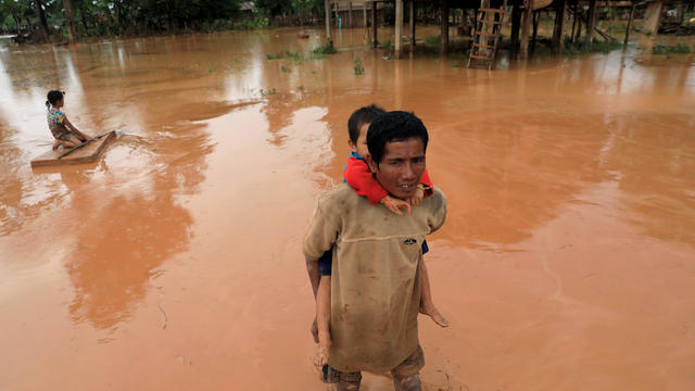 A man carries his child during the flood after the Xepian-Xe Nam Noy hydropower dam collapsed in Attapeu province 