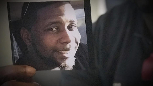 Michael McGlockton, unseen, holds a photo of his son, Markeis McGlockton, Aug. 7, 2018, in Clearwater, Fla. 