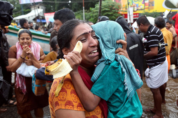 A woman cries as she holds her son after they were evacuated from a flooded area in Aluva 