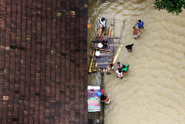 People wait for aid next to makeshift raft at a flooded area in the southern state of Kerala 