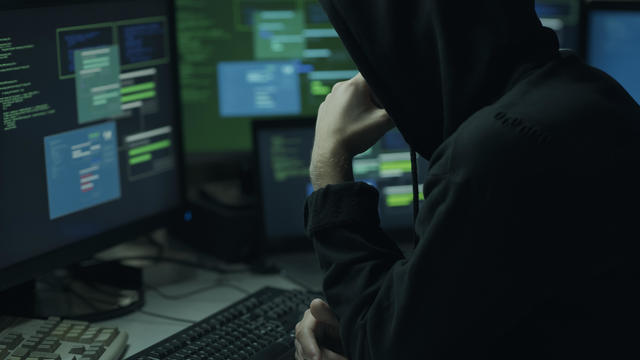 Hacker with hoodie on computer - cybersecurity, cyberattack, hacking - generic 