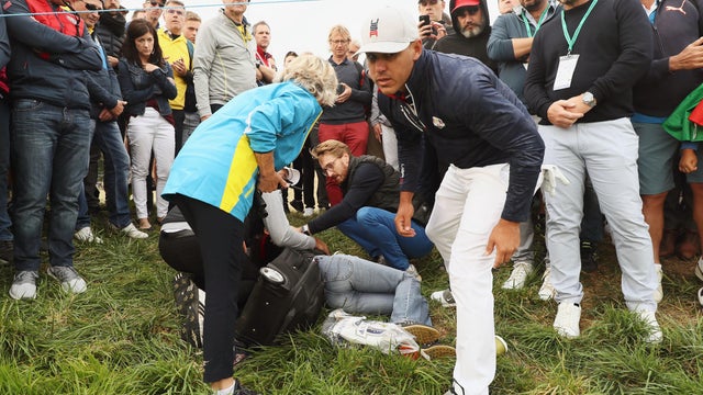 Brooks Koepka of the United States signs a glove and gives it to a woman who was hit by his ball on the sixth hole during the Ryder Cup at Le Golf National on Sept. 28, 2018, in Paris, France. 