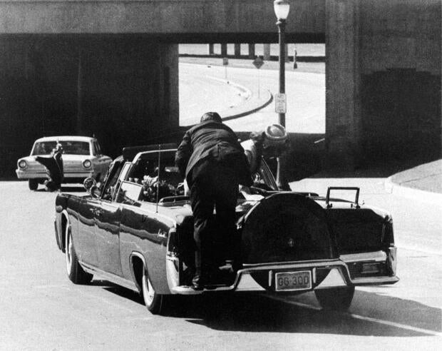 President John F. Kennedy slumps down in the back seat of the presidential limousine after he was fatally shot in Dallas on Nov. 22, 1963. Jacqueline Kennedy leans over the president as Secret Service agent Clinton Hill rides on the back of the car.