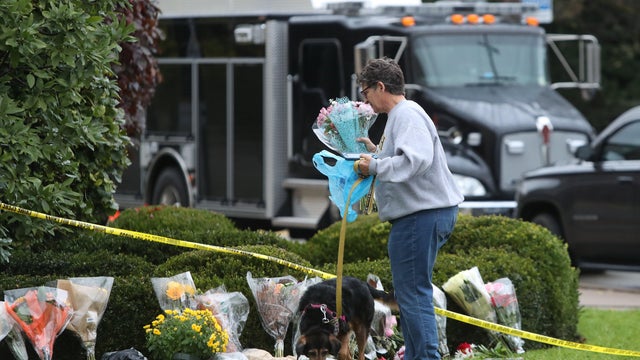 A woman brings flowers to an impromptu memorial at the Tree of Life synagogue following Saturday's shooting at the synagogue in Pittsburgh Pennsylvania 