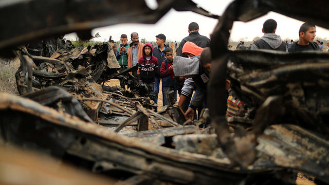 Palestinians gather around the remains of a vehicle that was destroyed in an Israeli air strike, in Khan Younis in the southern Gaza Strip 