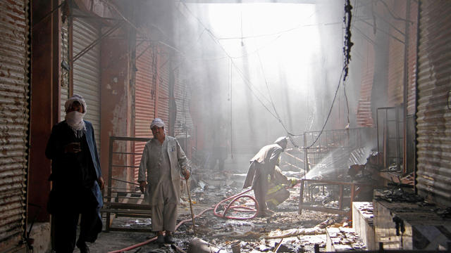 FILE PHOTO: An Afghan firefighter sprays water on burning shops after a Taliban attack in Ghazni city, 