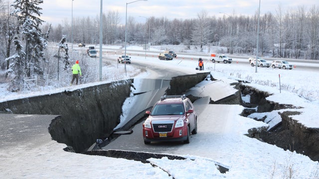 A vehicle lies stranded on a collapsed roadway near the airport after an earthquake in Anchorage 