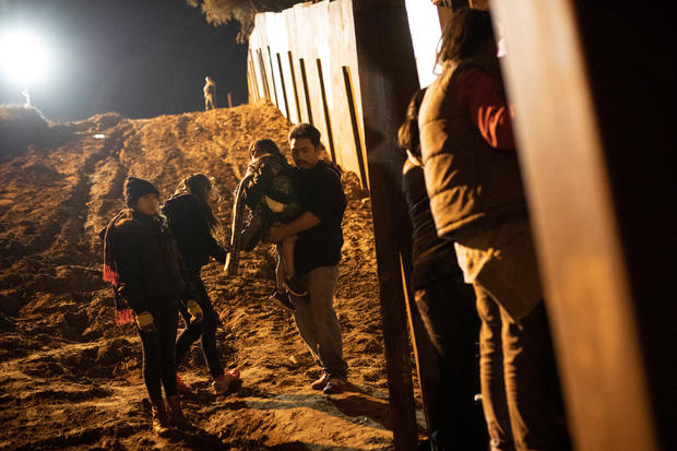 Migrants, part of a caravan of thousands from Central America trying to reach the United States, are seen in San Diego County, U.S., after crossing illegally from Mexico to the U.S by jumping a border fence, photographed through the border wall in Tijuana 