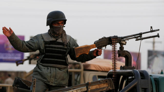 An Afghan policeman keeps watch at a back of truck at the site of an attack in Kabul 