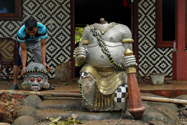 A worker lifts up a head of destroyed statue at the beach front hotel which was hit by a tsunami in Pandeglang 