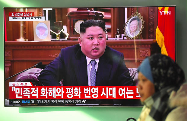A woman walks past a television screen showing a New Year's speech by North Korean leader Kim Jong Un at a railway station in Seoul on Jan. 1, 2019. 