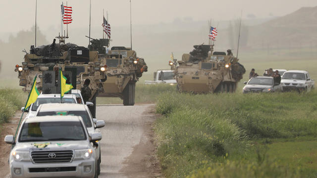 FILE PHOTO: Kurdish fighters from the People's Protection Units (YPG) head a convoy of U.S military vehicles in the town of Darbasiya next to the Turkish border 
