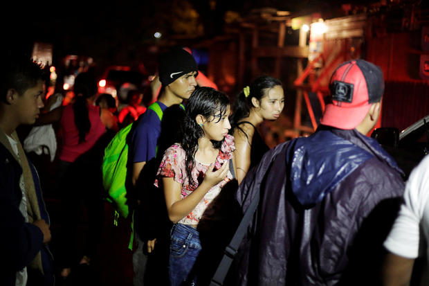 Hondurans, part of a new caravan of migrants travelling towards the United States, are seen as they wait to catch a ride in Cofradia 