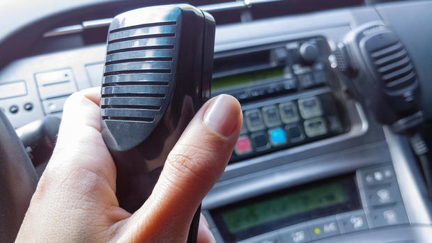 Police female officer holding Walkie-talkie in patrol car. Two-way radio. Police radio. Selective focus, close-up. 