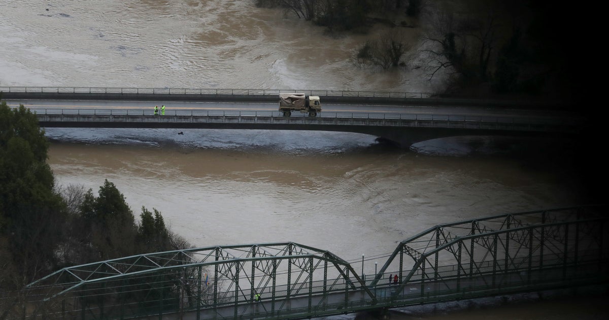 California town trapped by flood waters after river overflows - CBS News