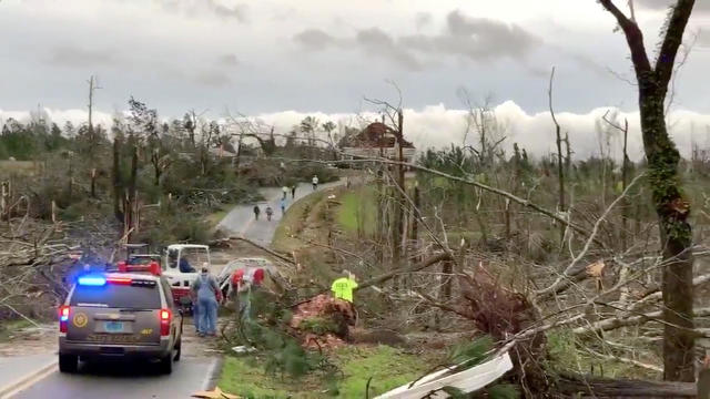 People clear fallen trees and debris on a road following a tornado in Beauregard, Alabama, U.S. in this March 3, 2019 still image obtained from social media video 