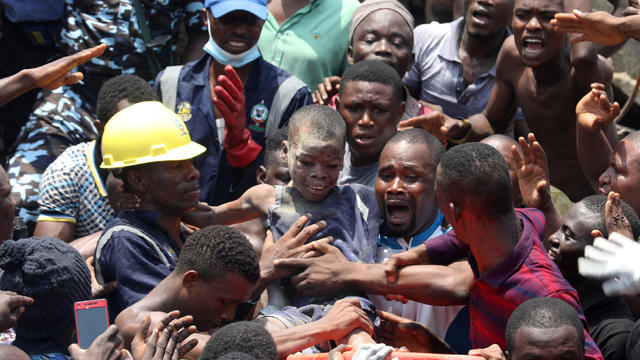 Men carry a boy who was rescued at the site of a collapsed building containing a school in Nigeria's commercial capital of Lagos 