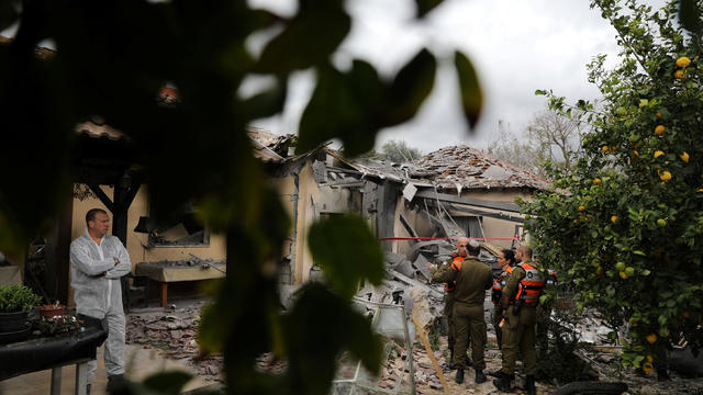 An Israeli police sapper and soldiers work next to a house that was hit by a rocket north of Tel Aviv, Israel 
