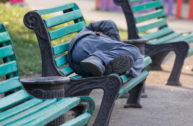 sleeping homeless man on a bench 