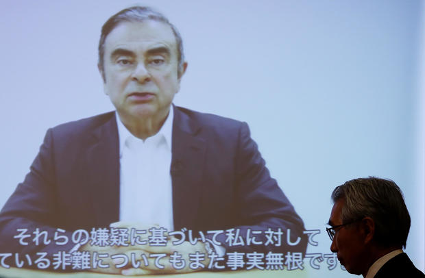 Junichiro Hironaka, chief lawyer of the former Nissan Motor chairman Carlos Ghosn, walks in front of a screen showing Ghosn's video statement during a news conference at Foreign Correspondents' Club of Japan in Tokyo 