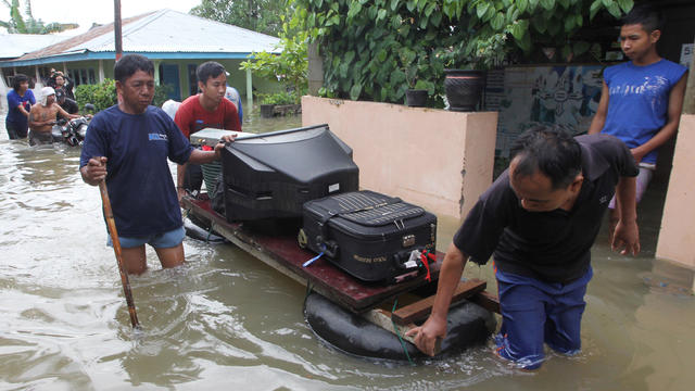 Residents carry their belongings with a raft through the flood in Bengkulu 