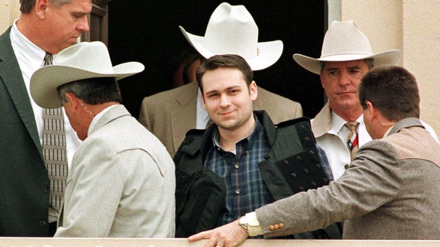 John William King (C) grins as he is led from the 