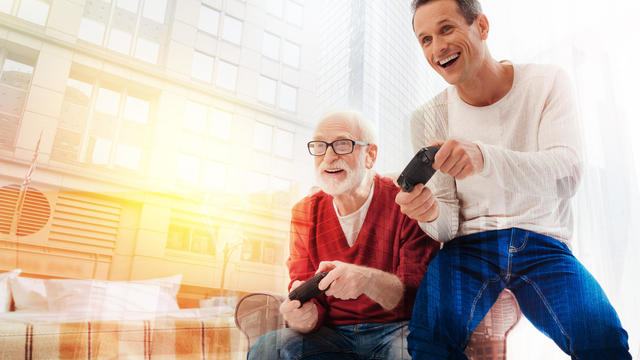 Excited pensioner playing computer games with his son 