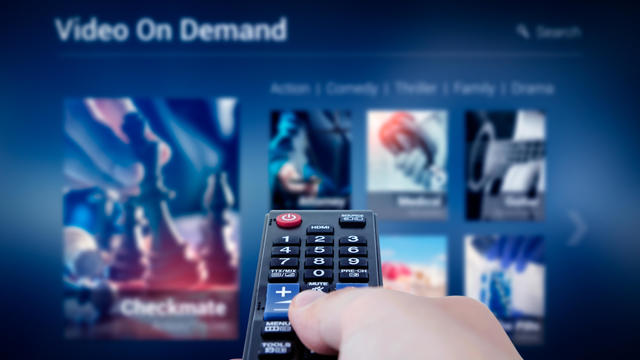 VOD service screen with remote control in hand 