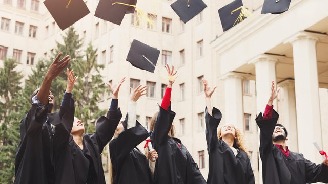 A group of graduates throwing graduation caps in the air 