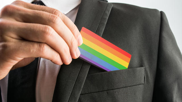 Man withdrawing wooden card painted as the gay pride flag 